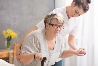 caregiver helping the senior woman to stand up