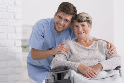 male caregiver and senior woman are smiling